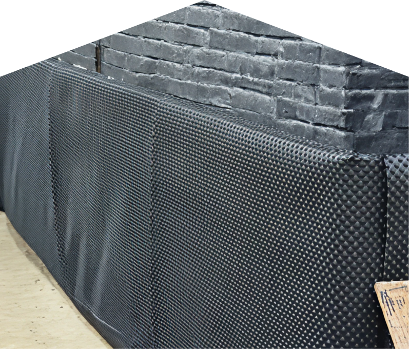 Exterior basement waterproofing completed by Limcan, showing a sealed foundation wall with dimpled waterproof membrane partially installed on a brick surface, preventing moisture infiltration. Exterior basement waterproofing completed by Limcan, showing a sealed foundation wall with dimpled waterproof membrane partially installed on a brick surface, preventing moisture infiltration.