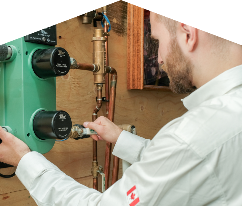 Limcan HVAC specialist performing boiler installation, securing a valve on a new hydronic heating system with copper piping and a green circulation pump mounted on a wooden wall. Limcan HVAC specialist performing boiler installation, securing a valve on a new hydronic heating system with copper piping and a green circulation pump mounted on a wooden wall.