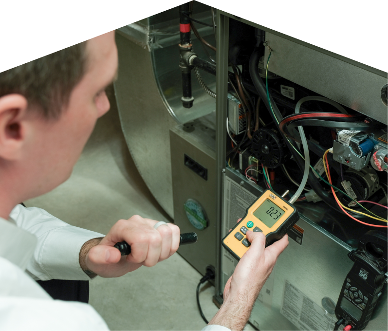 Limcan HVAC specialist performing furnace repair on a heating system, using a digital manometer to check pressure. Limcan HVAC specialist performing furnace repair on a heating sy