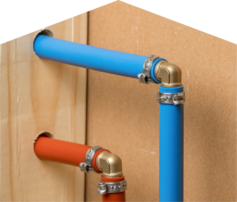 Limcan kitec plumbing system with blue and orange plastic pipes connected by brass fittings and metal clamps, mounted on a wooden panel. Limcan kitec plumbing system with blue and orange plastic pipes connected by brass fittings and metal clamps, mounted on a wooden panel.