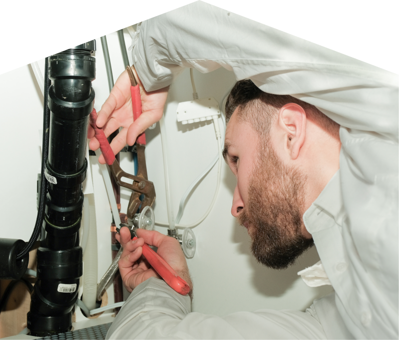 Limcan plumbing specialist uses hand tools to tighten pipe fittings beneath a sink during a repair, with visible wiring and drainage lines in the background. Limcan plumbing specialist uses hand tools to tighten pipe fittings beneath a sink during a repair, with visible wiring and drainage lines in the background.