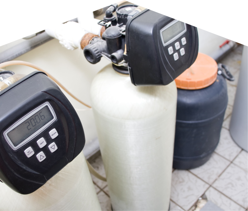 Limcan water softener installation showing dual resin tanks with digital control heads and a brine tank in a tiled utility area. Limcan water softener installation showing dual resin tanks with digital control heads and a brine tank in a tiled utility area.